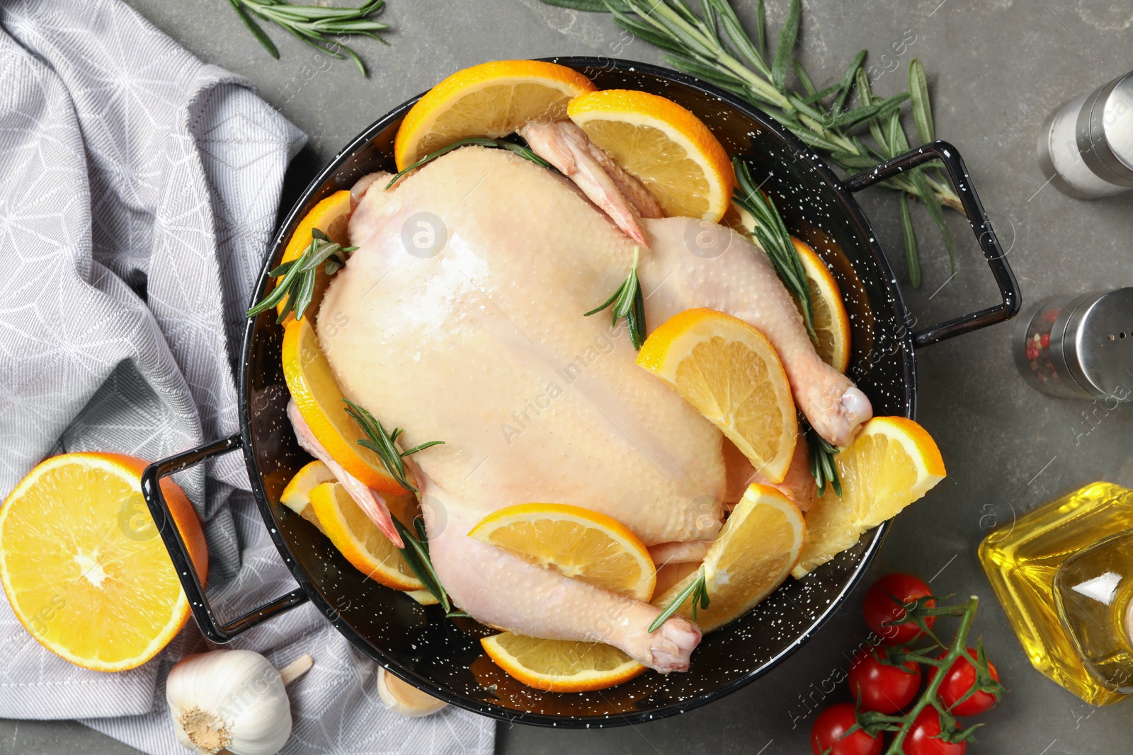 Photo of Chicken with orange slices and ingredients on grey table, flat lay