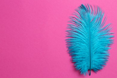 Photo of Beautiful light blue feather on pink background, top view. Space for text