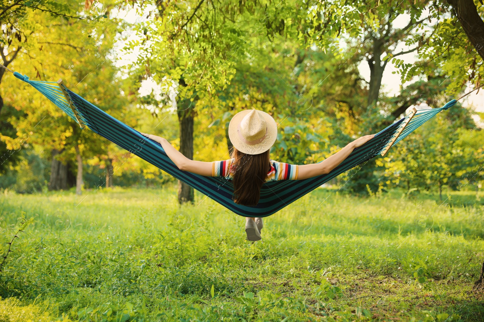 Photo of Young woman resting in comfortable hammock at green garden