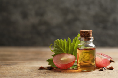 Photo of Bottle of natural grape seed oil on wooden table, space for text. Organic cosmetic