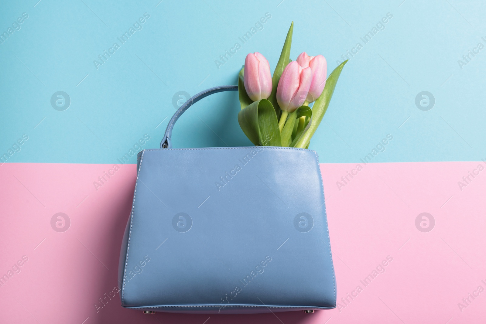 Photo of Flat lay composition with stylish woman's handbag and spring flowers on color background