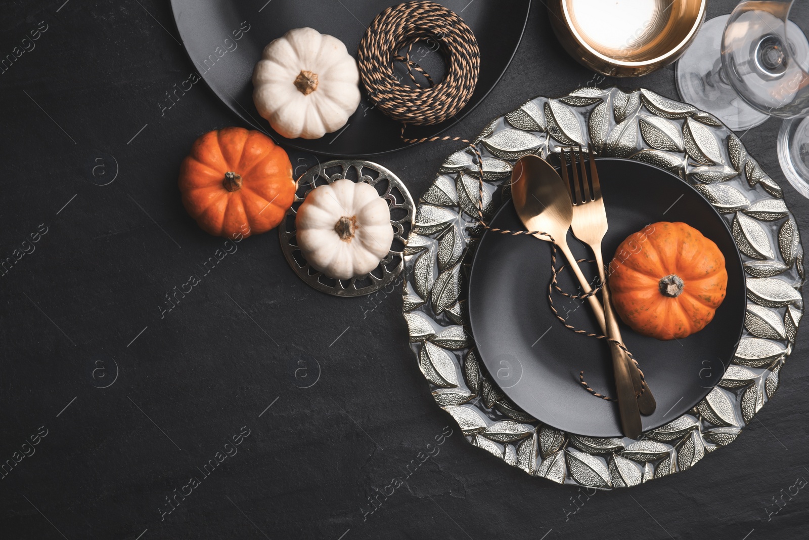 Photo of Autumn table setting with golden cutlery and pumpkins on black background, flat lay. Space for text