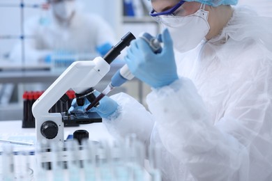 Photo of Scientist dripping sample onto glass slide while working with microscope in laboratory