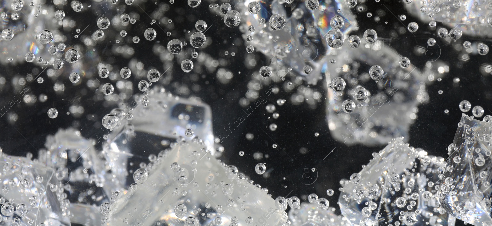 Image of Soda water with ice cubes against dark background, closeup. Banner design