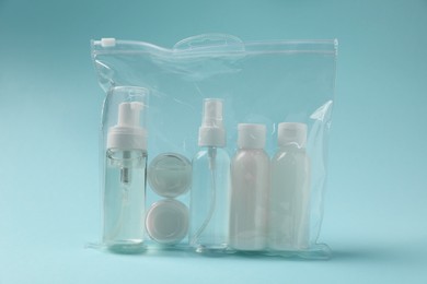 Photo of Cosmetic travel kit in plastic bag on light blue background. Bath accessories