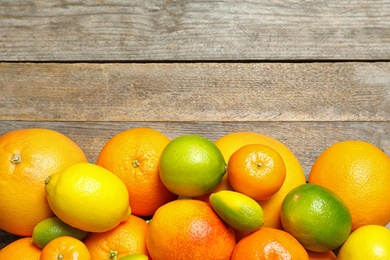 Flat lay composition with different citrus fruits and space for text on wooden background