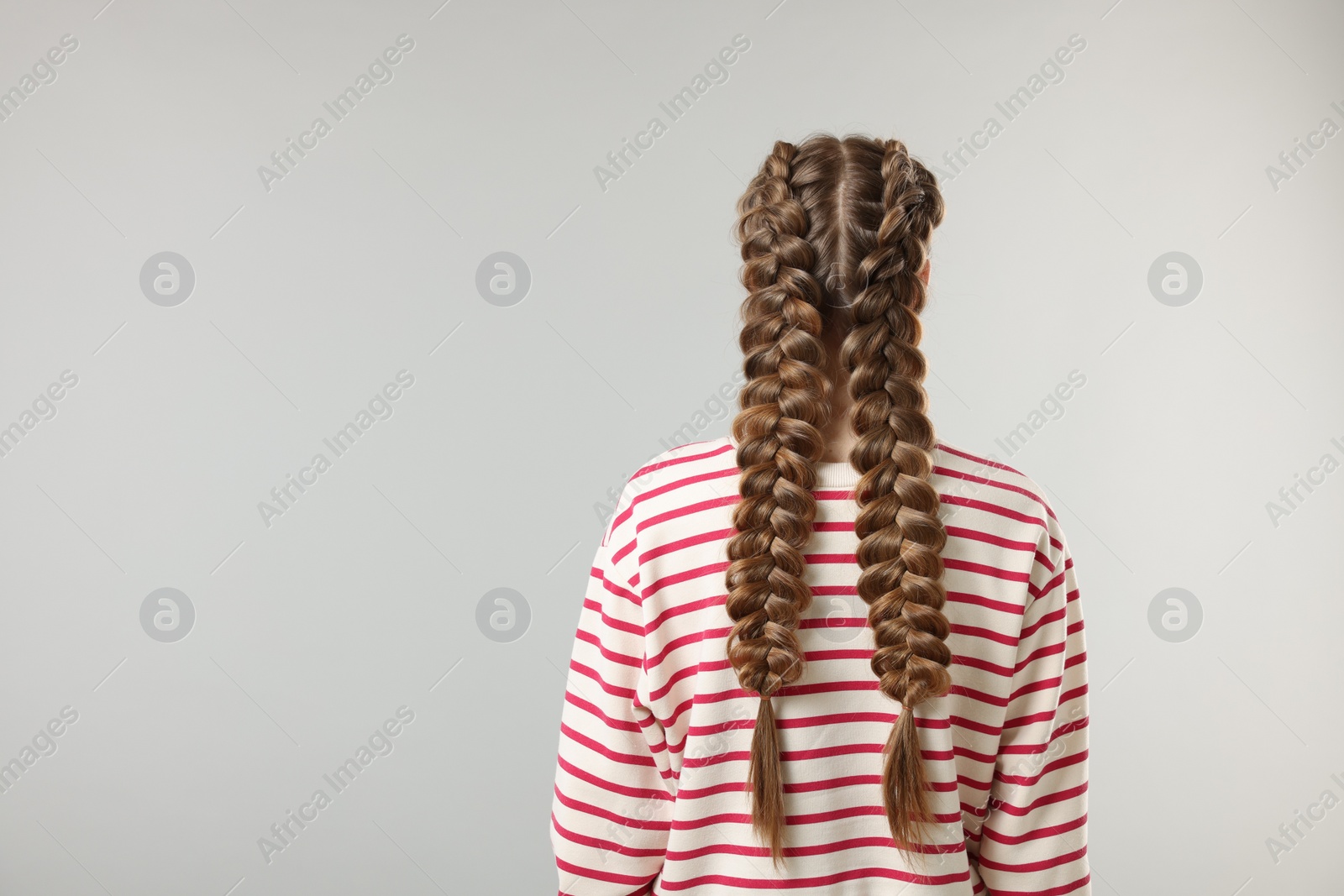 Photo of Woman with braided hair on grey background, back view. Space for text