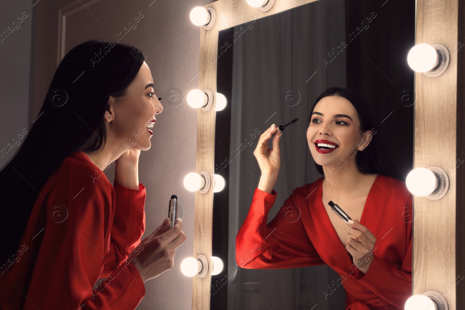 Photo of Beautiful woman applying makeup near mirror in room