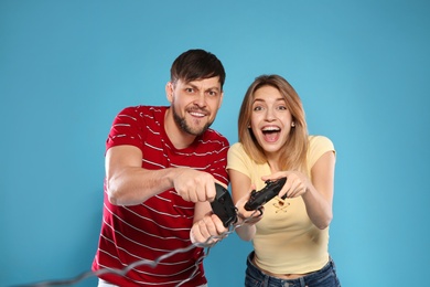 Photo of Emotional couple playing video games with controllers on color background