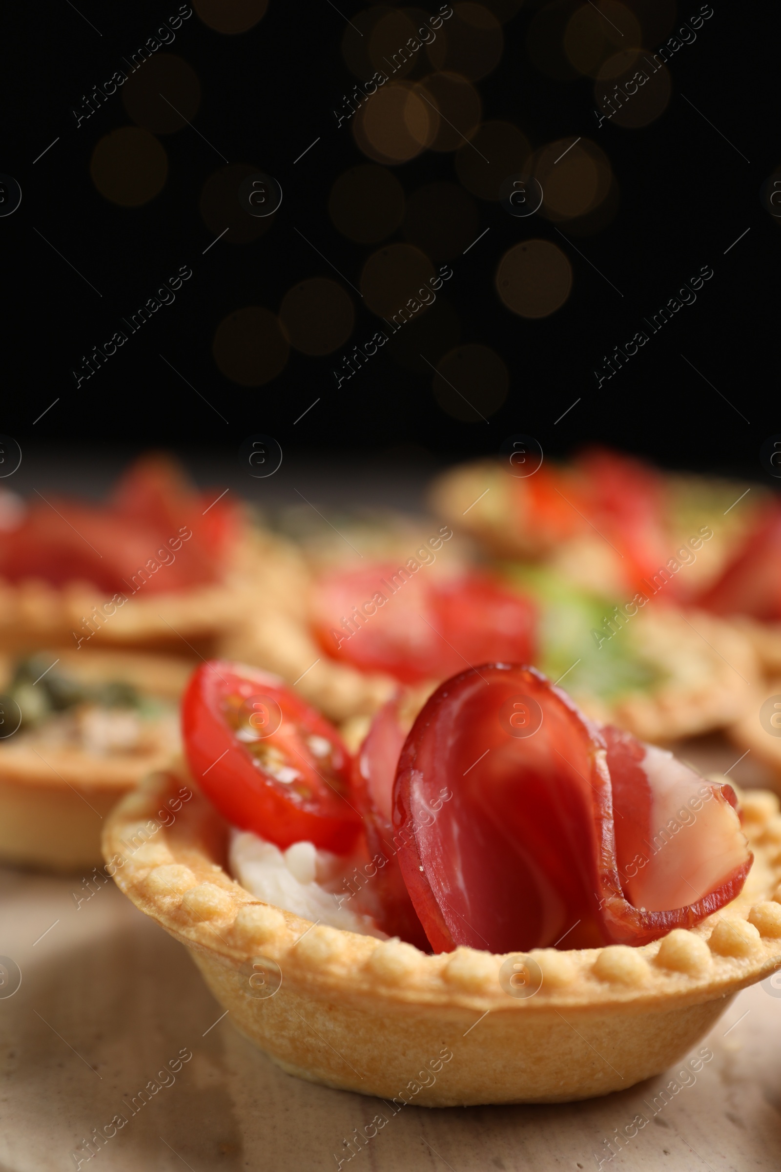 Photo of Delicious canapes with jamon, cream cheese and tomato on table, closeup