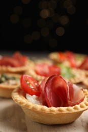 Delicious canapes with jamon, cream cheese and tomato on table, closeup