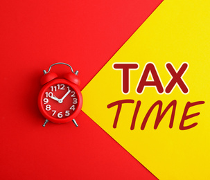 Image of Time to pay taxes. Alarm clock on color background, top view