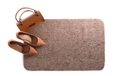 Photo of Stylish door mat with high heeled shoes and bag on white background, top view