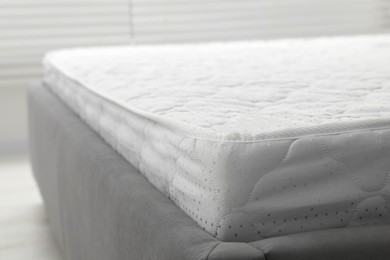 Photo of New light green mattress on gray bed indoors, closeup. Space for text