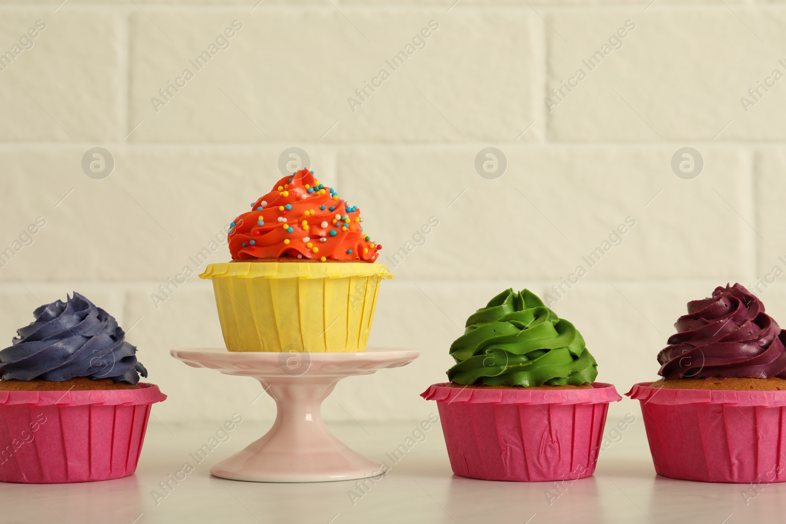 Photo of Delicious cupcakes with colorful cream on white table
