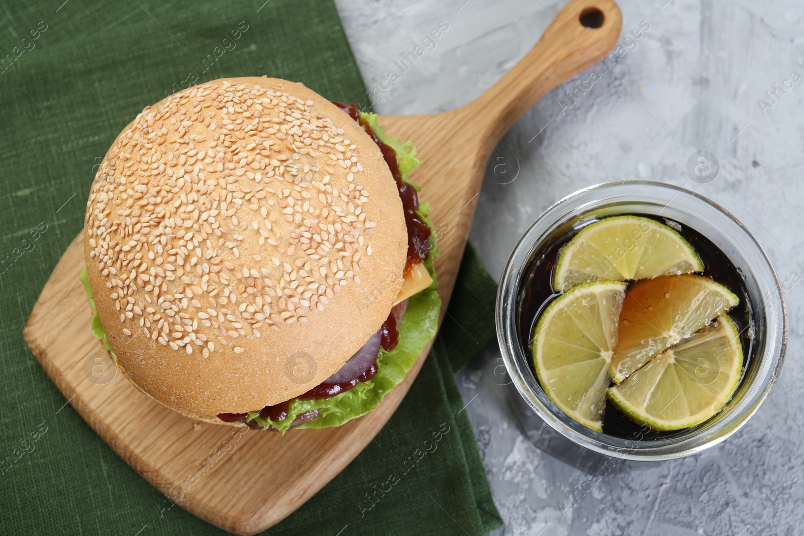 Photo of Delicious cheeseburger and drink on grey textured table, top view