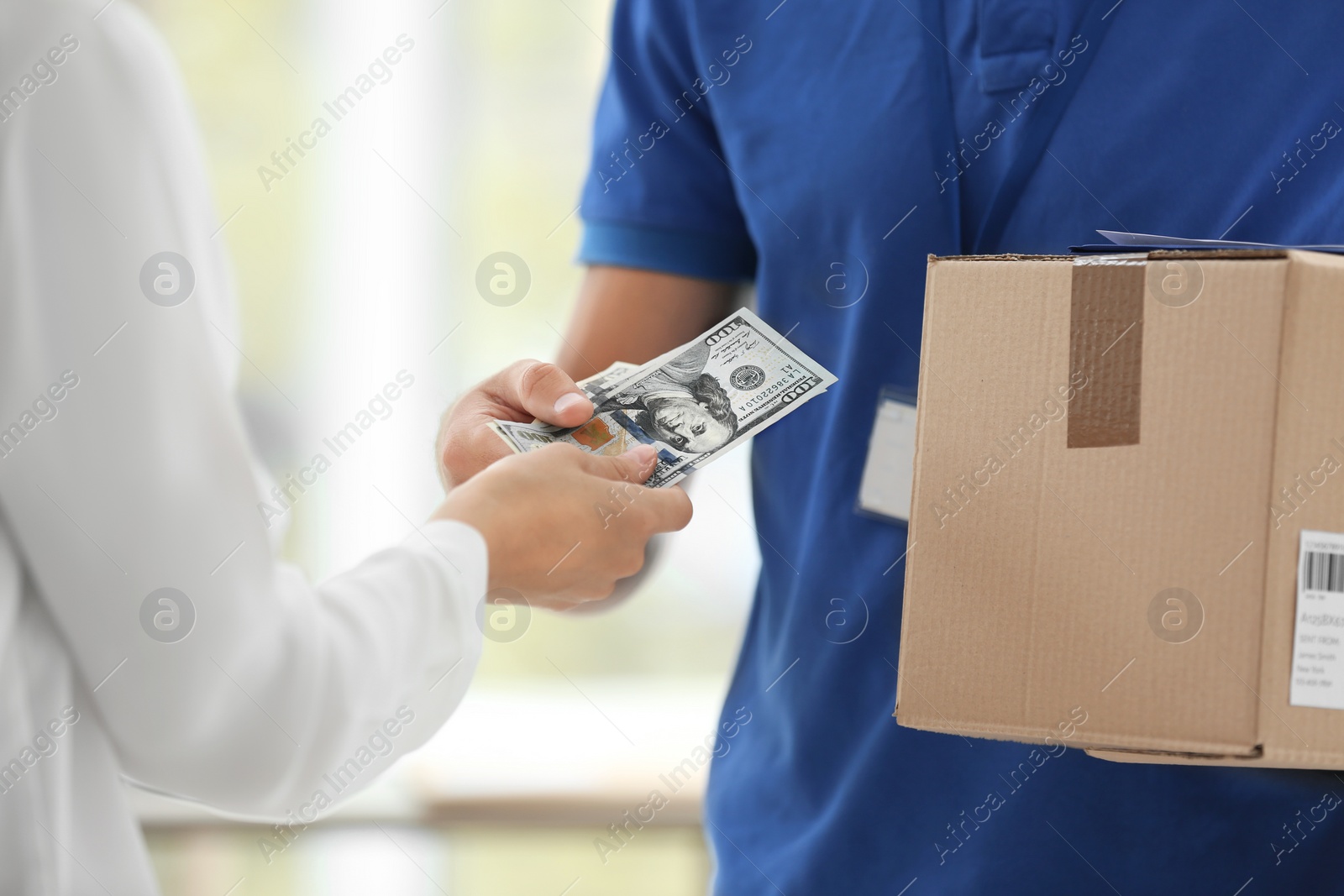 Photo of Young woman paying for delivered parcel indoors. Courier service