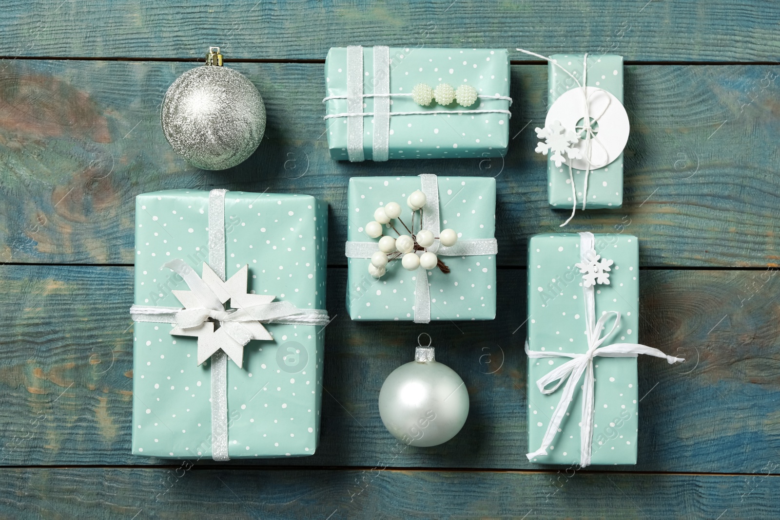 Photo of Gift boxes with Christmas balls on blue wooden background, flat lay