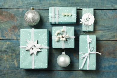 Photo of Gift boxes with Christmas balls on blue wooden background, flat lay