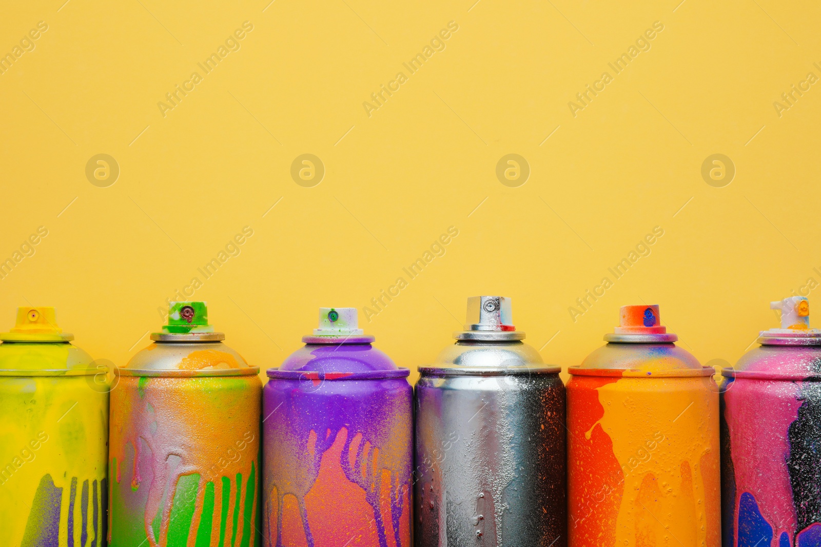 Photo of Used cans of spray paints on beige background, flat lay with space for text. Graffiti supplies