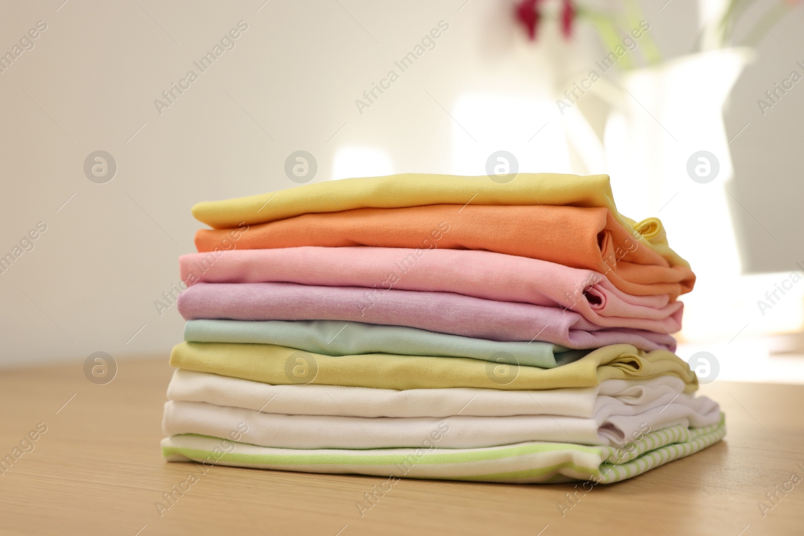 Photo of Stack of clean clothes on wooden table