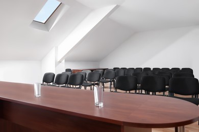 Photo of Large wooden table and many chairs in empty conference room