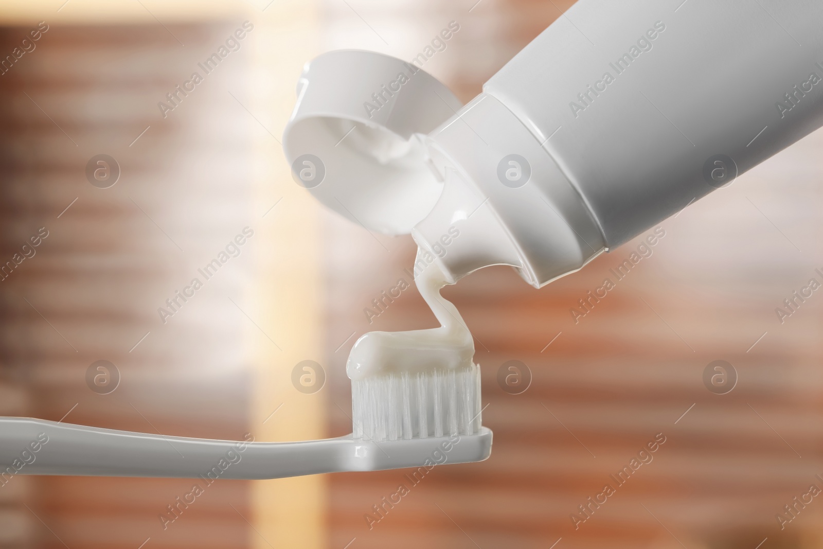 Photo of Applying paste on toothbrush against blurred background, closeup