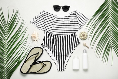 Photo of Flat lay composition with striped swimsuit and beach accessories on light stone background