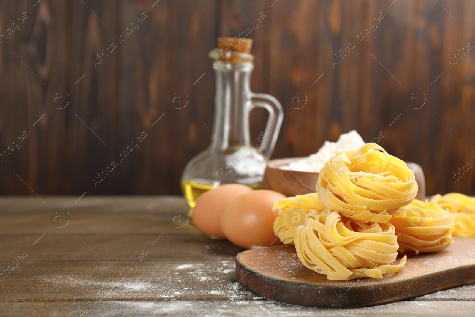 Photo of Raw noodles and ingredients on wooden table, space for text