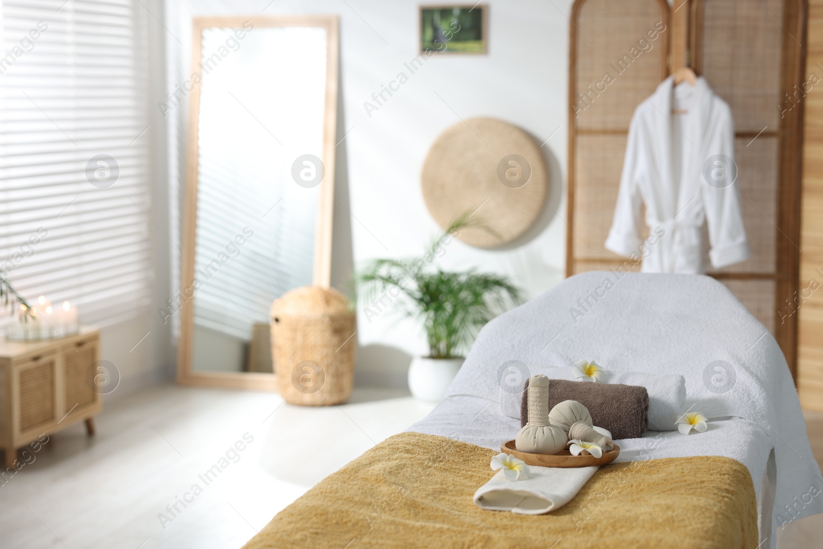 Photo of Herbal bags, flowers and towels on massage table in spa center