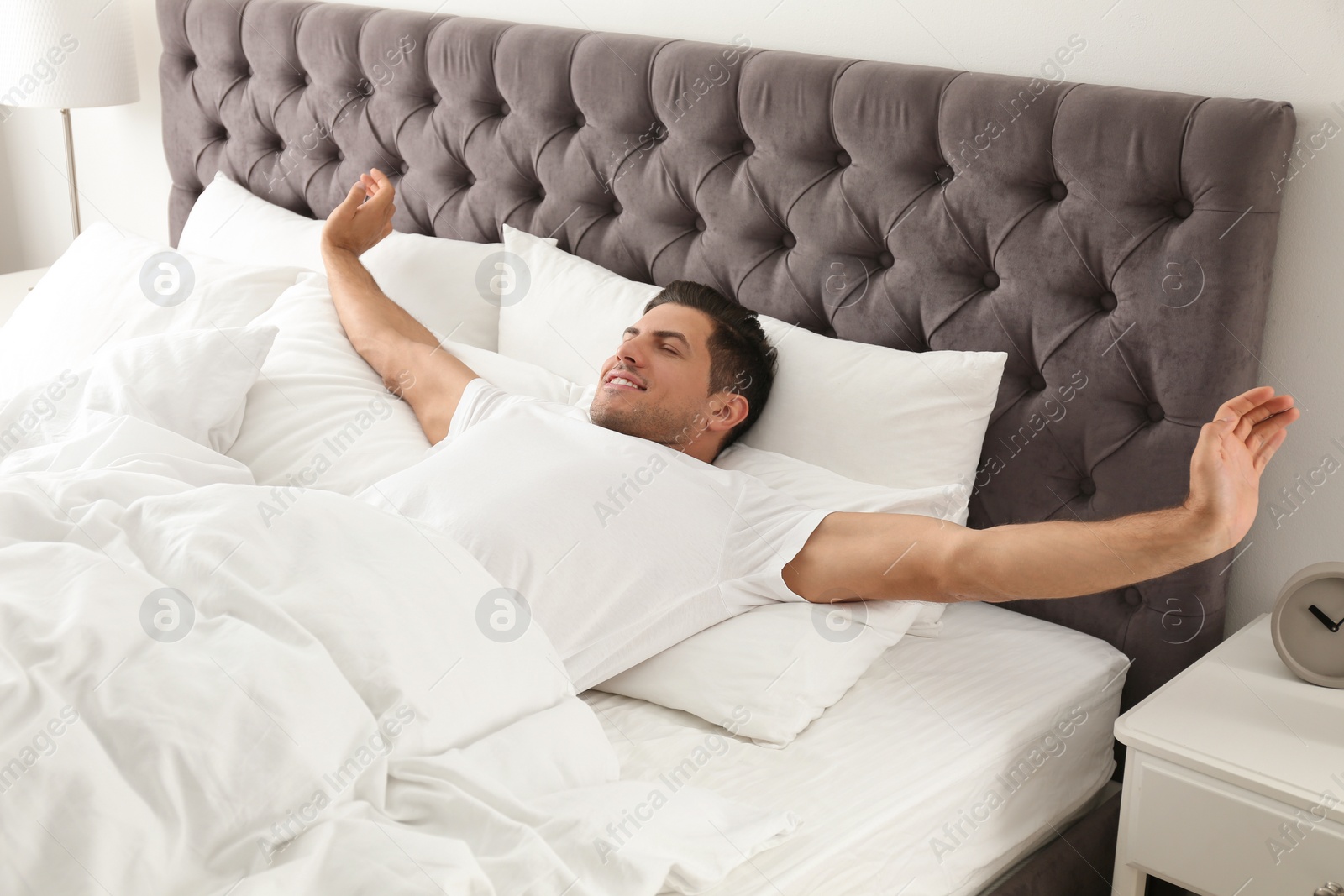 Photo of Man awakening on bed at home. Lazy morning