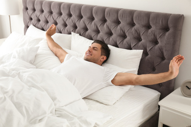 Photo of Man awakening on bed at home. Lazy morning