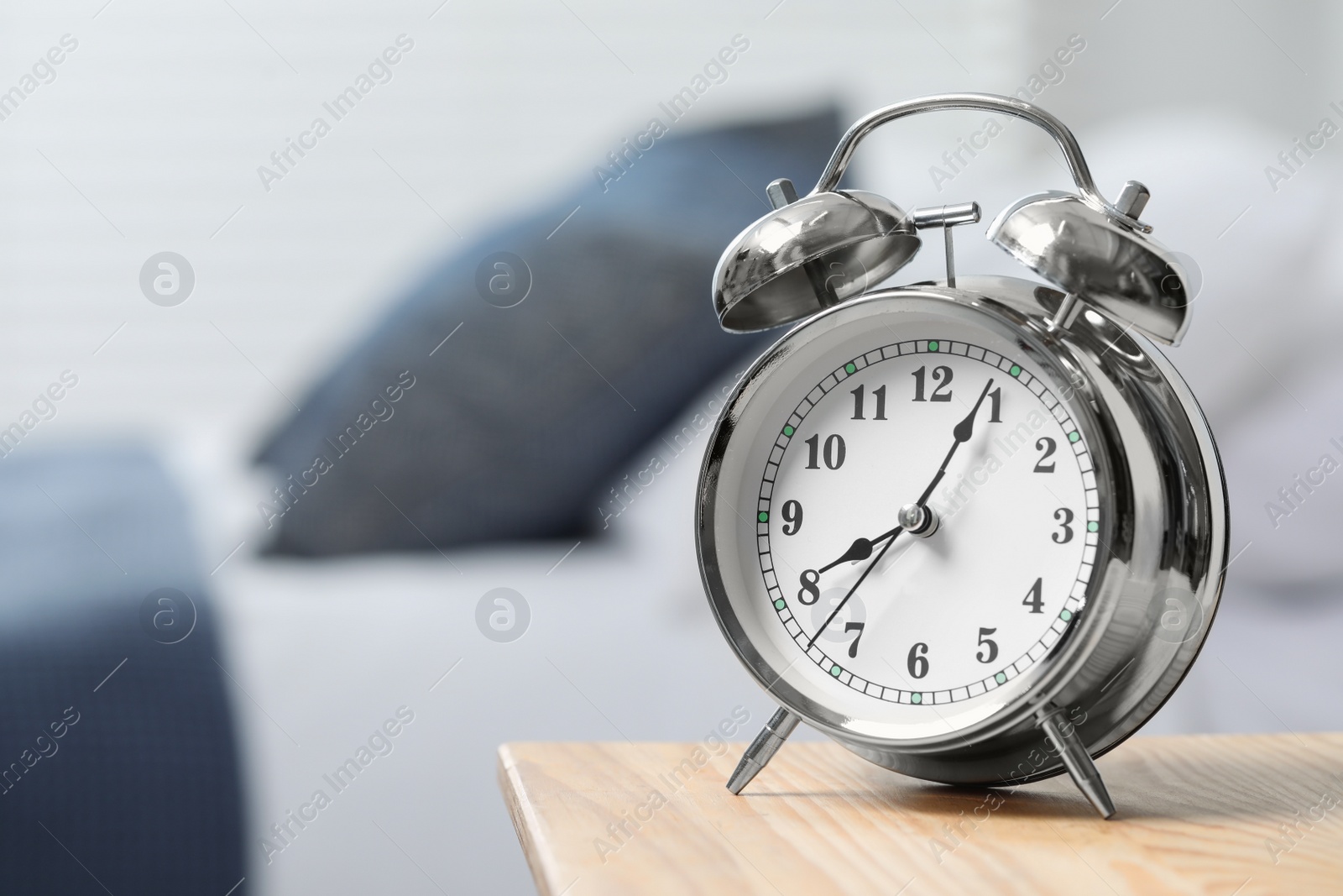 Photo of Silver alarm clock on wooden nightstand in bedroom, space for text