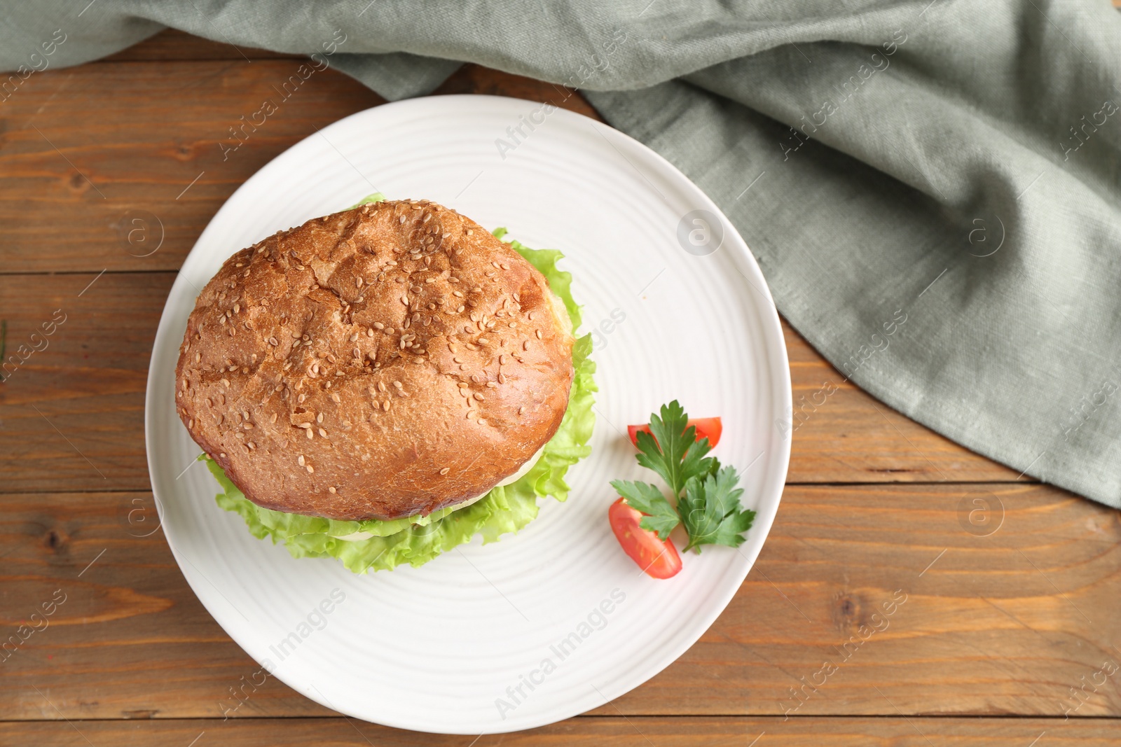 Photo of Delicious vegetarian burger served on wooden table, top view