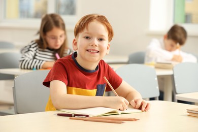 Photo of Portrait of smiling little boy studying in classroom at school