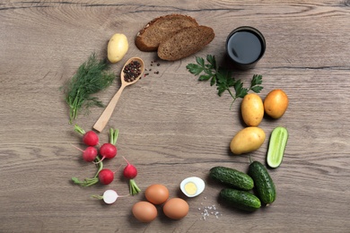 Frame of kvass and other okroshka ingredients on wooden table, flat lay with space for text. Traditional Russian summer soup