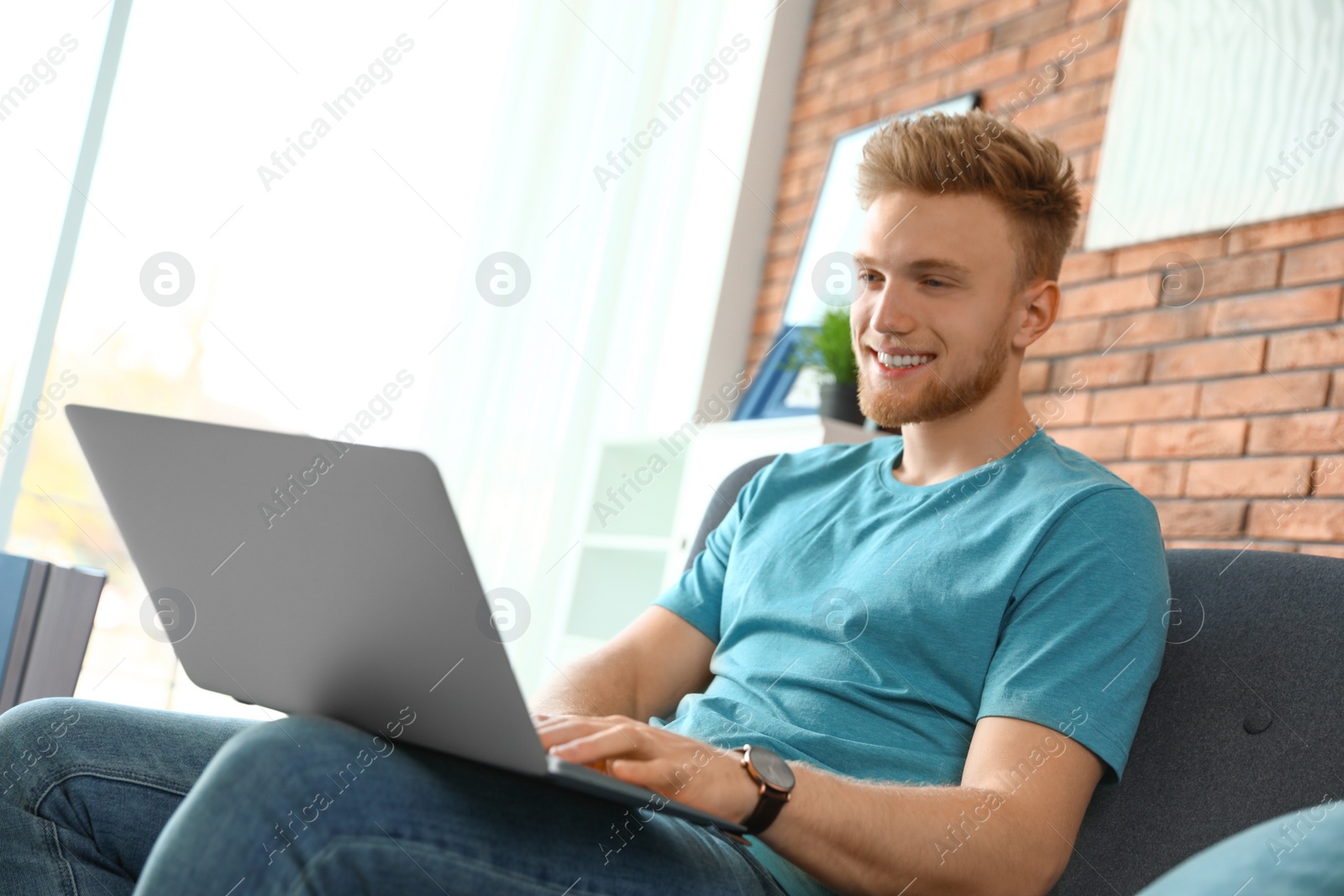 Photo of Young man using laptop in living room