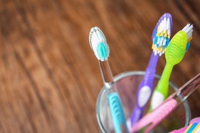 Photo of Cup with toothbrushes on wooden table, closeup. Dental care