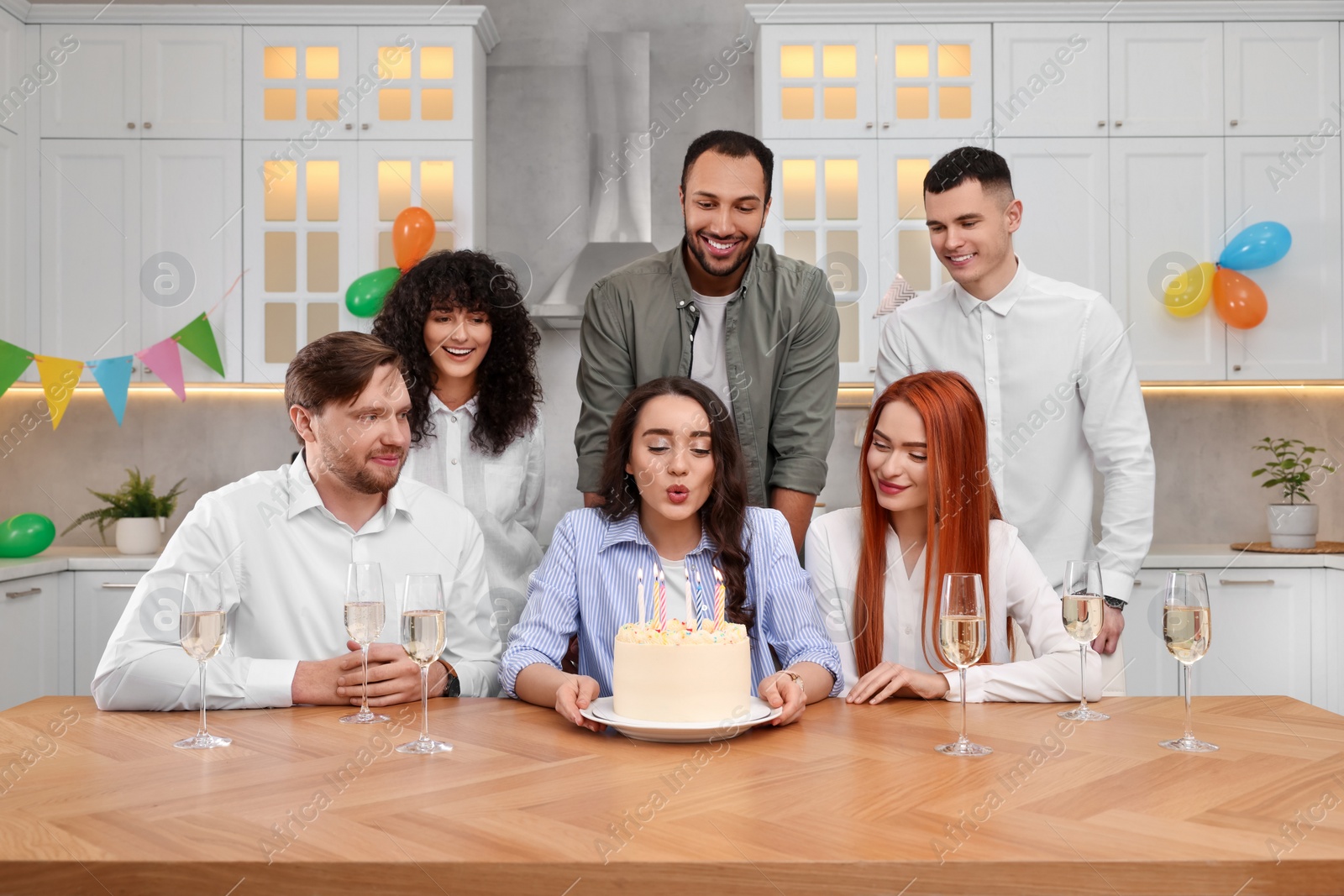 Photo of Happy friends with tasty cake celebrating birthday in kitchen