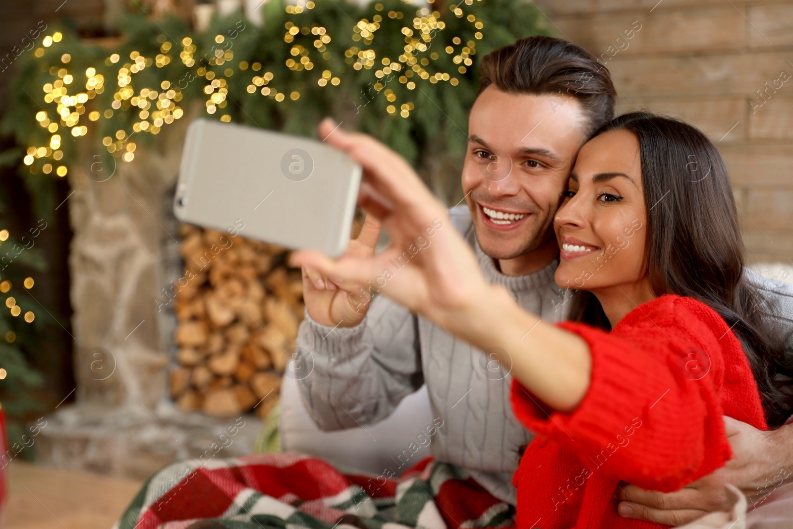 Photo of Happy young couple taking selfie in living room decorated for Christmas