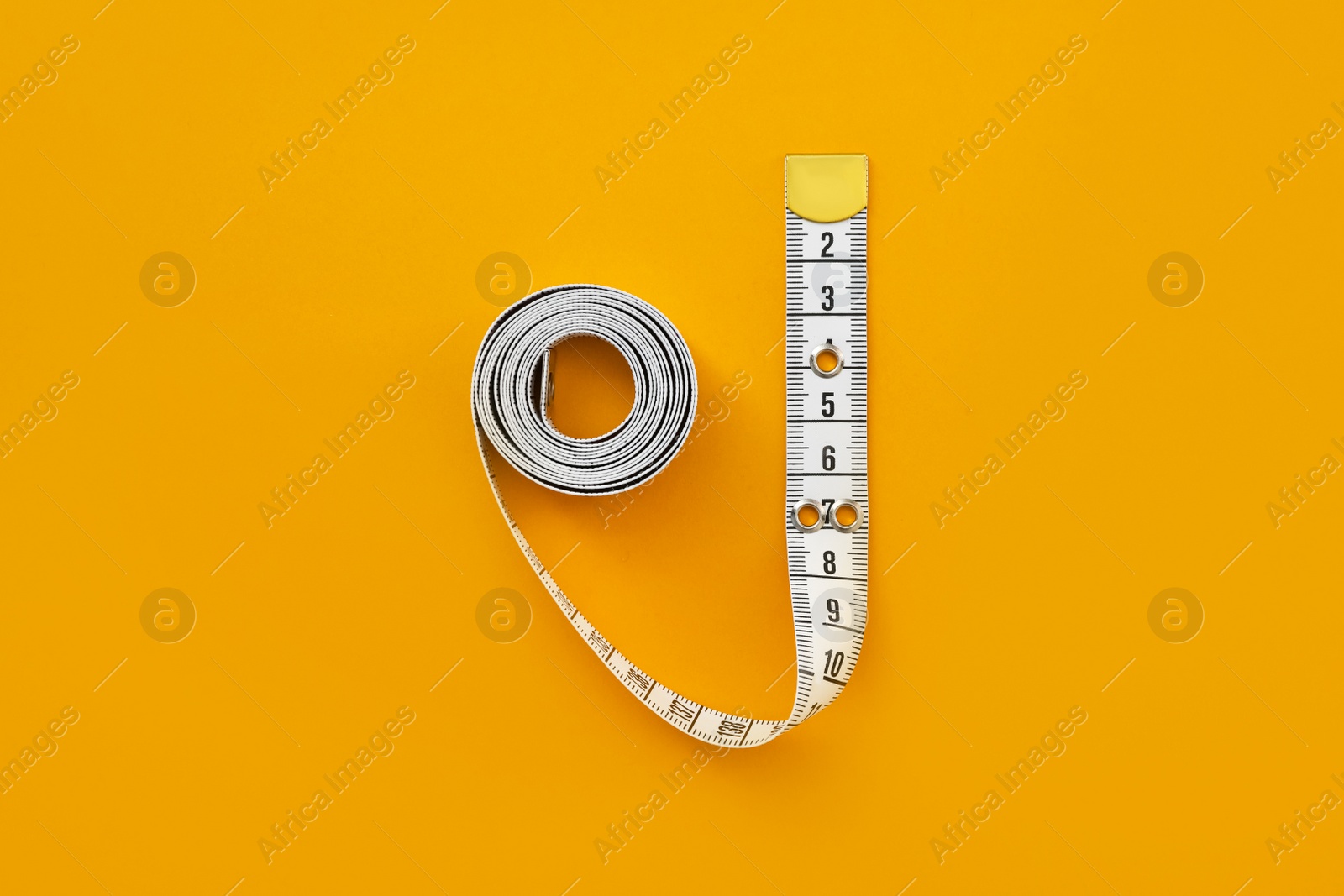 Photo of White measuring tape on orange background, top view