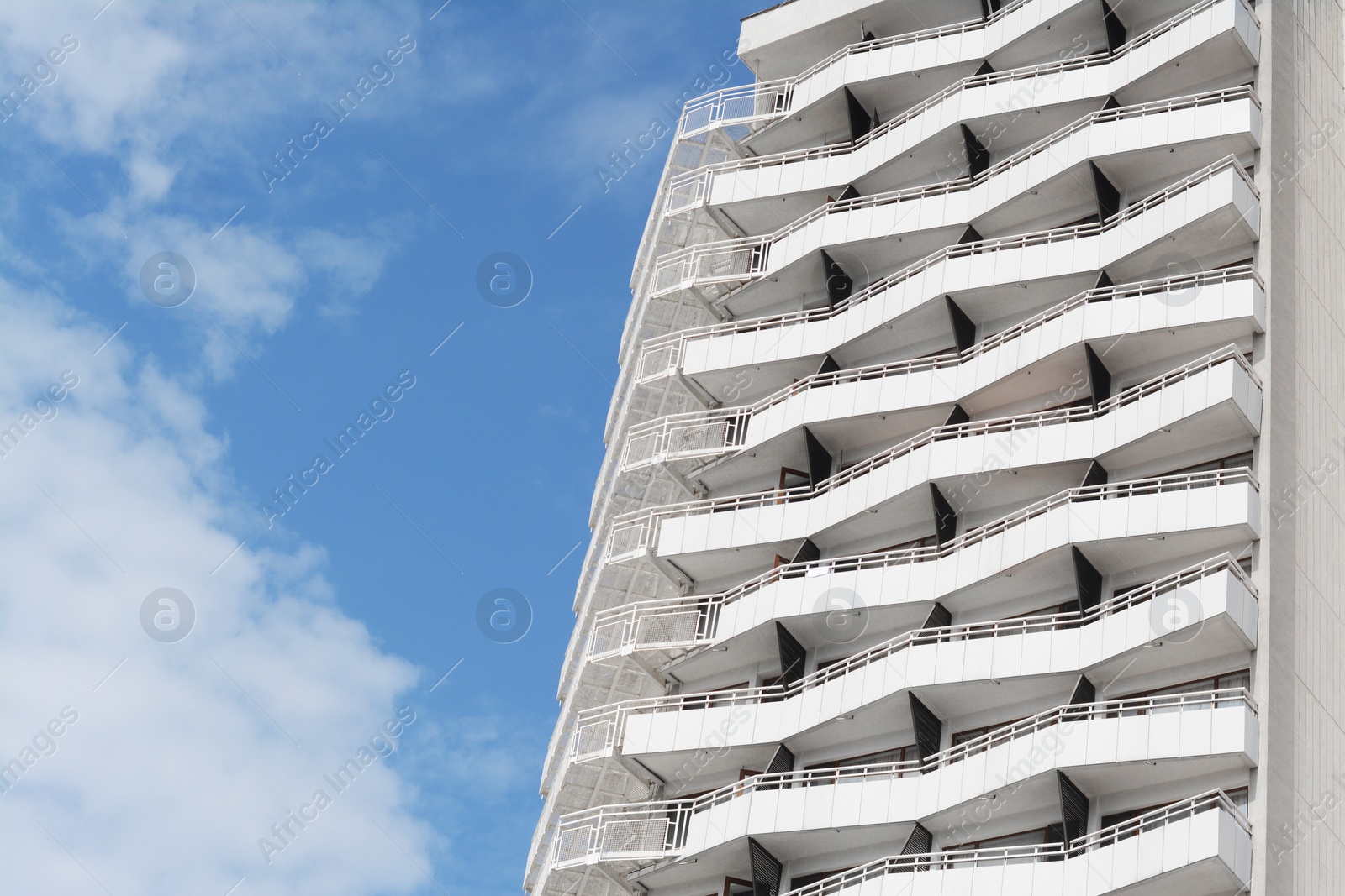 Photo of Exterior of beautiful building with balconies against blue sky, low angle view. Space for text