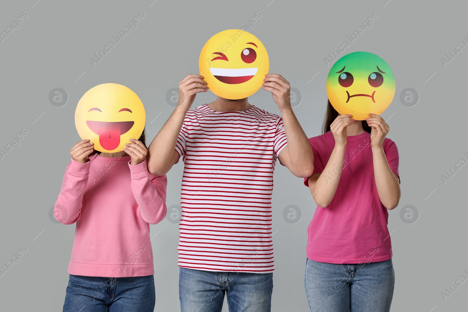 Photo of People covering faces with emoticons on grey background