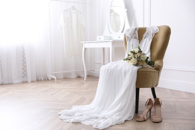Photo of Elegant wedding dress, shoes and bouquet in room