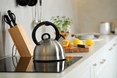 Photo of Stylish kettle with whistle on cooktop in kitchen. Space for text
