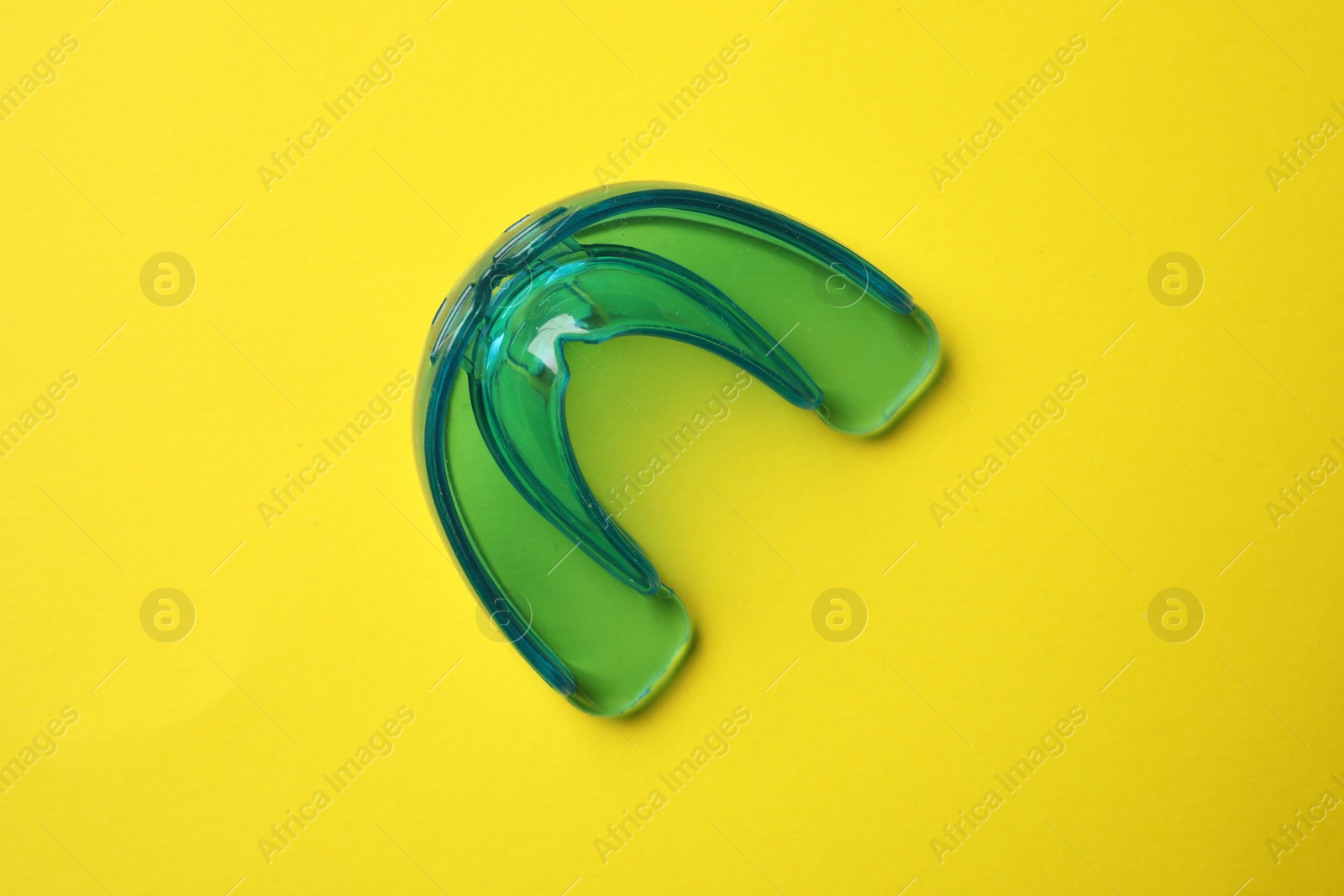 Photo of Dental mouth guard on yellow background, top view. Bite correction