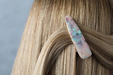 Young woman with beautiful hair clip on blue background, closeup