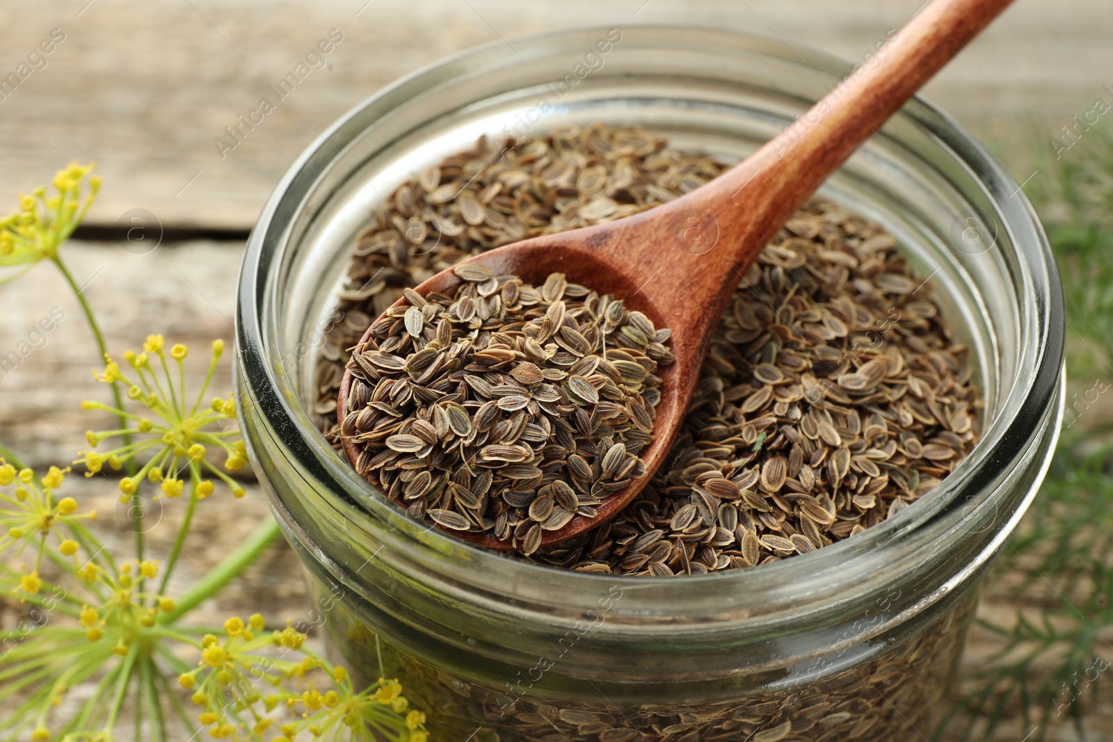 Photo of Jar with dry dill seeds and spoon on wooden table, closeup