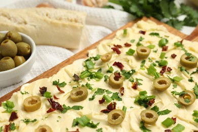 Photo of Fresh butter board with cut olives, onion and sun-dried tomatoes on table, closeup