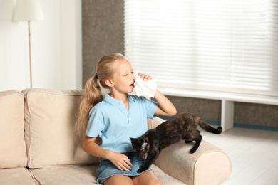 Photo of Little girl with cat suffering from allergy at home